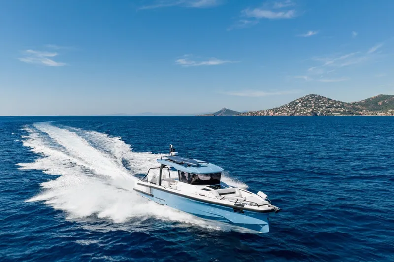 Slide: The Image of 2027 Axopar 38 Cross Top cruising on open sea with scenic coastal backdrop. - 7