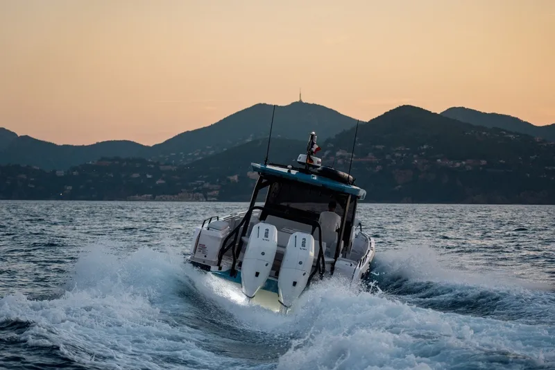 Slide: The Image of 2027 Axopar 38 Cross Top navigating at sunset with mountainous backdrop. - 20