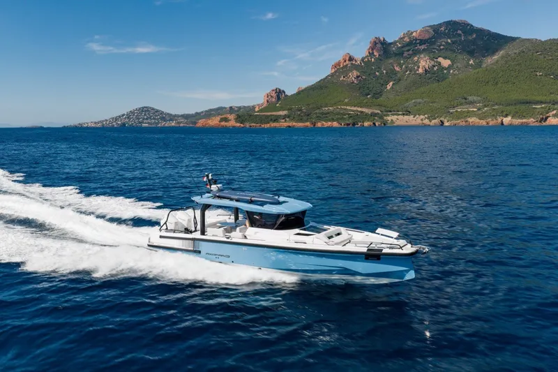 Slide: The Image of 2027 Axopar 38 Cross Top cruising on blue ocean near scenic coastline. - 8