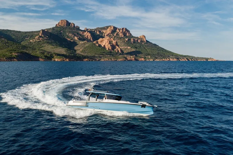 Slide: The Image of 2027 Axopar 38 Cross Top cruising near scenic coastal cliffs. - 11