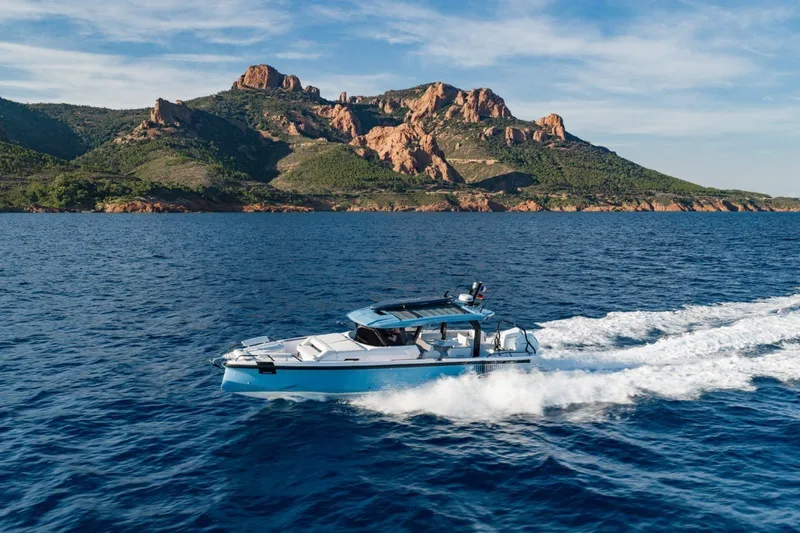 Slide: The Image of 2027 Axopar 38 Cross Top cruising near scenic rocky coastline. - 10