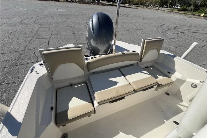 Slide: The Image of 2019 Stingray 236 CC boat with cushioned seating and outboard motor in a parking area. - 15
