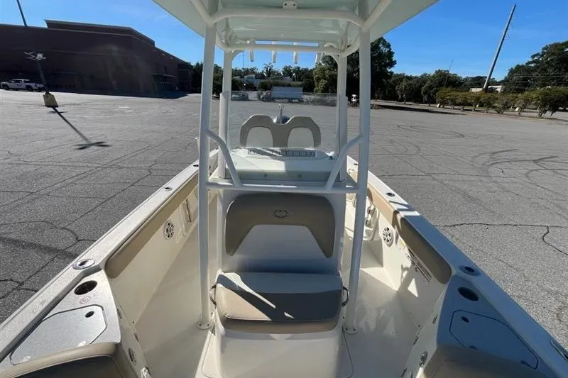 Slide: The Image of 2019 Stingray 236 CC boat interior with seating and console in a parking lot. - 14