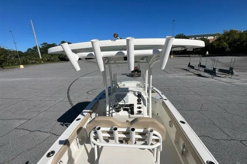 Slide: The Image of 2019 Stingray 236 CC boat with rod holders, parked in an empty lot under clear blue skies. - 12
