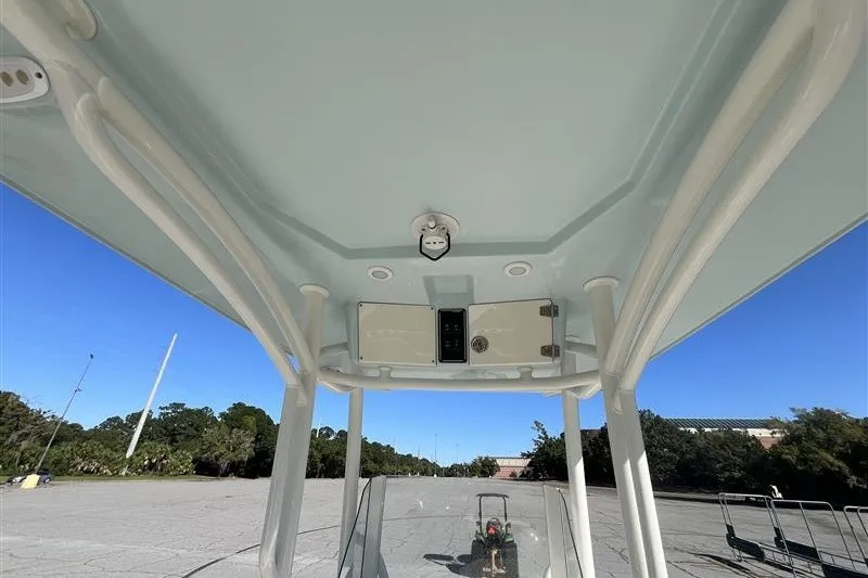Slide: The Image of 2019 Stingray 236 CC boat interior view with overhead console and clear sky. - 19