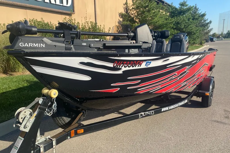 Slide: The Image of 2014 Lund 1650 Rebel XL SS boat with vibrant red and black graphics on a trailer. - 1