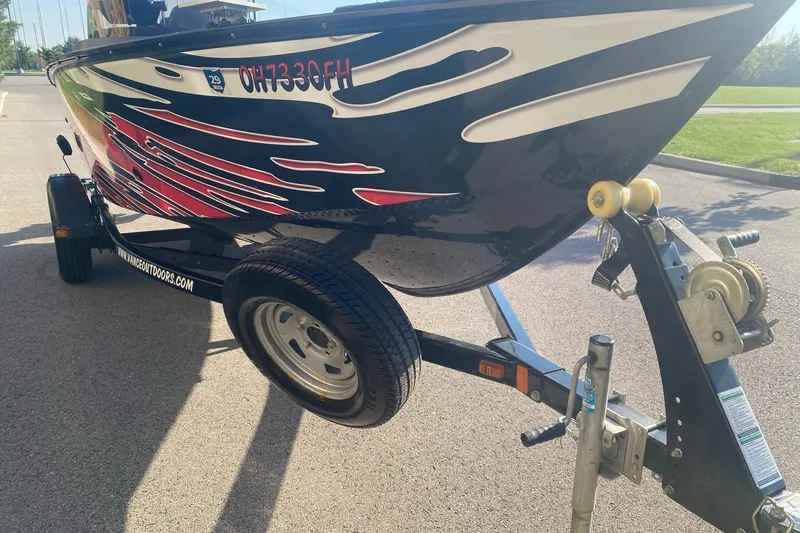 Slide: The Image of 2014 Lund 1650 Rebel XL SS boat on trailer with vibrant graphics. - 3