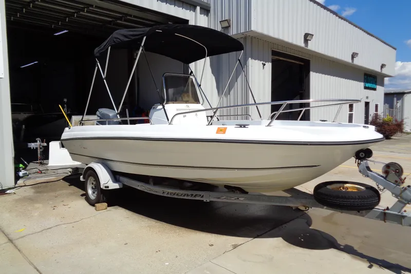 Slide: The Image of 2004 Triumph 190 Bay boat on trailer outside a garage, featuring a canopy and sleek design. - 15