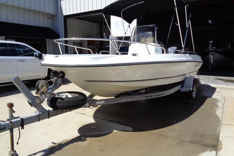 Slide: The Image of 2004 Triumph 190 Bay boat on trailer, parked outdoors in sunlight. - 2