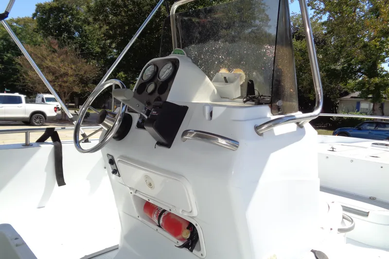 Slide: The Image of 2004 Triumph 190 Bay boat console with steering wheel and gauges, parked outdoors. - 7