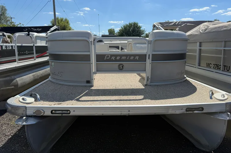 Slide: The Image of 2003 Premier 24 pontoon boat with gray deck, parked outdoors under blue sky. - 2