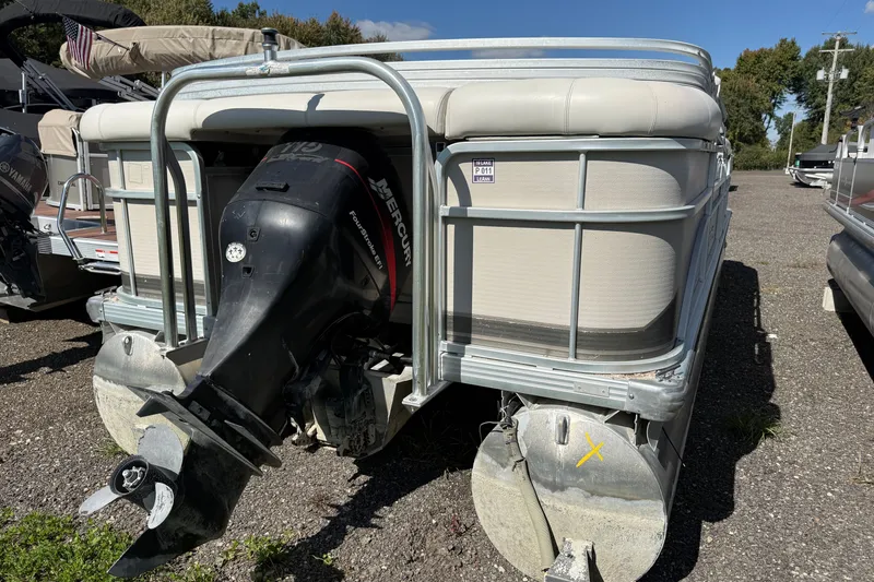 Slide: The Image of 2003 Premier 24 pontoon boat with Mercury outboard motor, parked on gravel lot. - 4