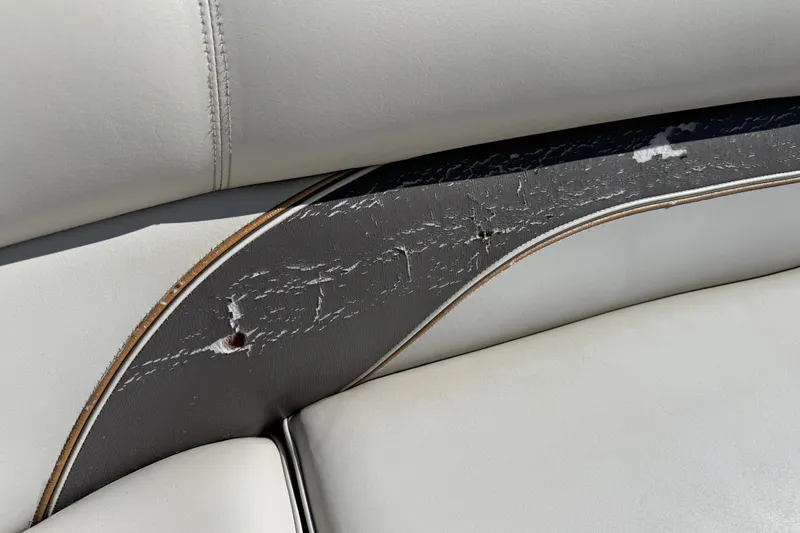Slide: The Image of Worn upholstery on a 2003 Premier 24 boat seat, showing visible cracks and damage. - 8