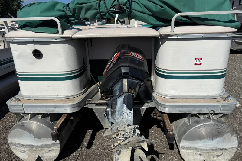 Slide: The Image of 1997 Sweetwater 24es pontoon boat with Mercury outboard motor, covered and parked on pavement. - 11