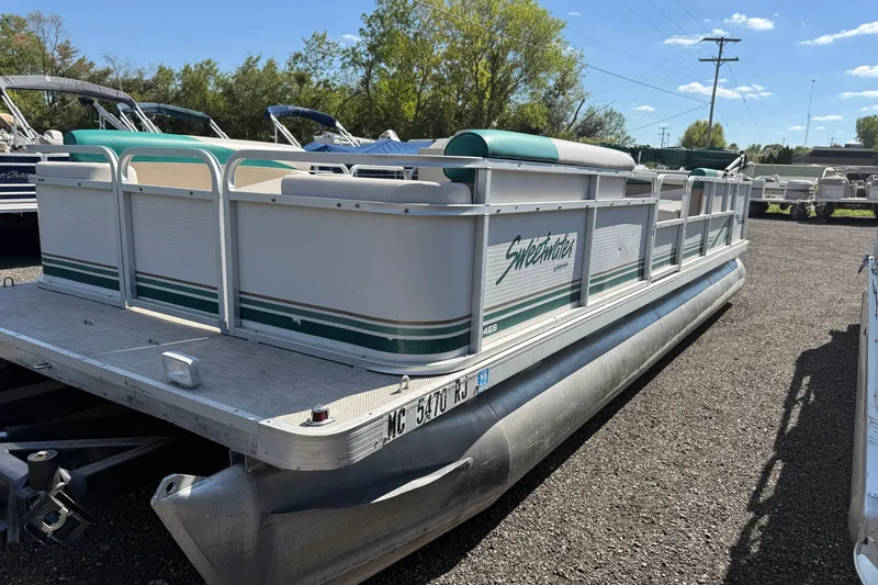 Slide: The Image of 1997 Sweetwater 24es pontoon boat parked on gravel lot under clear sky. - 1