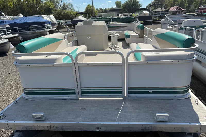 Slide: The Image of 1997 Sweetwater 24es pontoon boat with green and white seating, docked outdoors. - 2