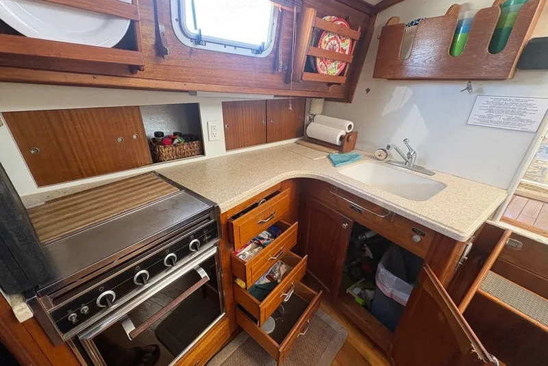 Slide: The Image of 1975 Gulfstar 43 Trawler kitchen with stove, sink, wooden cabinets, and open storage spaces. - 39