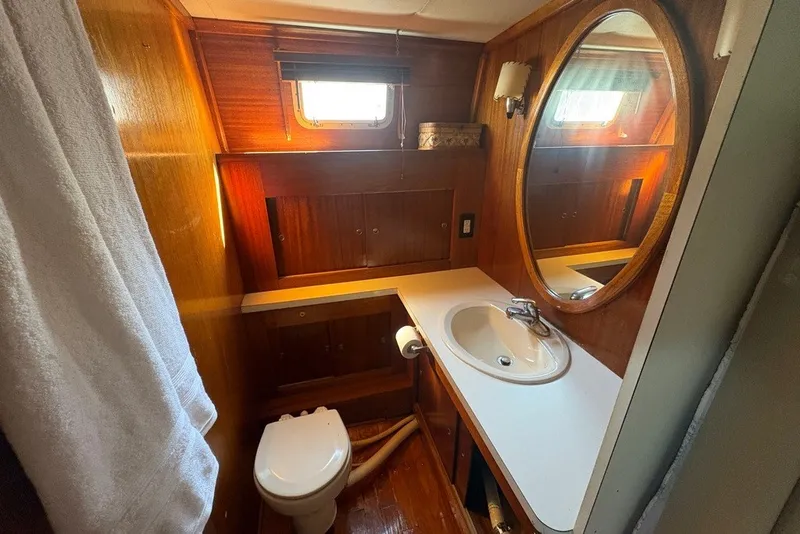 Slide: The Image of 1975 Gulfstar 43 Trawler bathroom with wood paneling, oval mirror, and sink. - 55