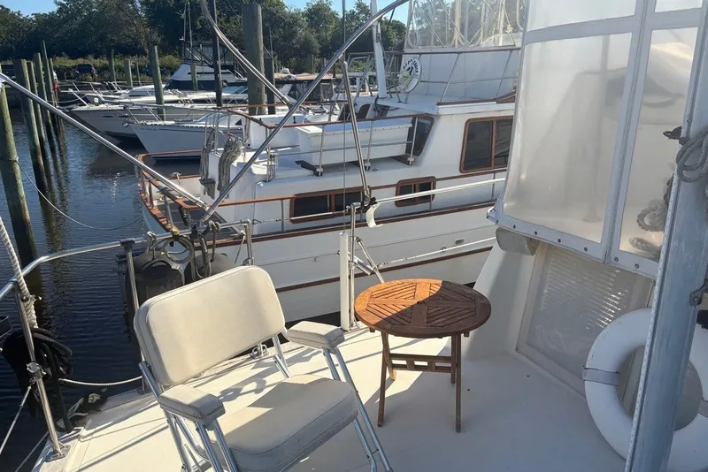Slide: The Image of 1975 Gulfstar 43 Trawler docked, featuring deck chairs and a small wooden table. - 78