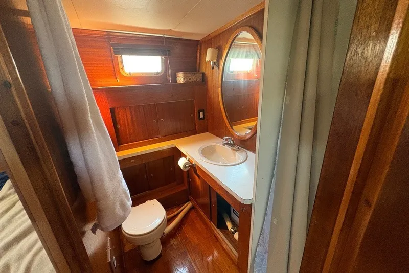 Slide: The Image of 1975 Gulfstar 43 Trawler bathroom with wooden cabinetry, sink, and round mirror. - 54
