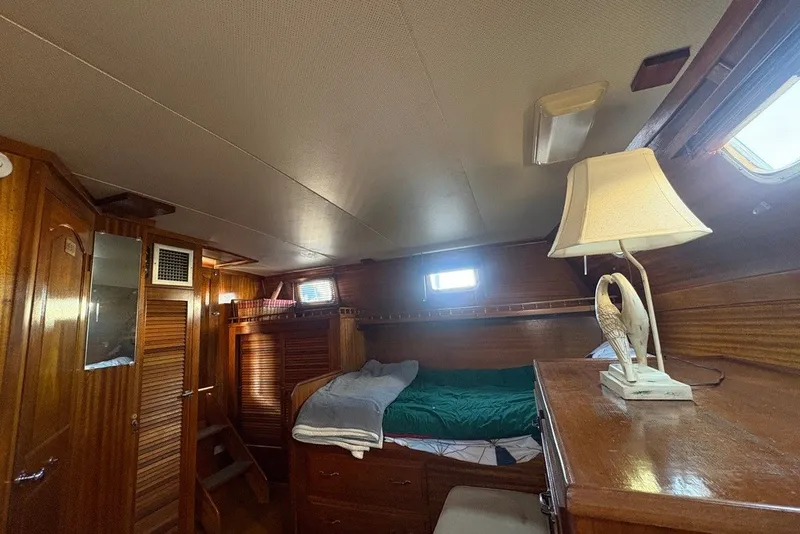 Slide: The Image of Cozy cabin interior of a 1975 Gulfstar 43 Trawler with wooden furnishings and a decorative lamp. - 60