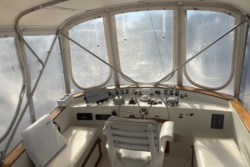 Slide: The Image of 1975 Gulfstar 43 Trawler helm with Garmin navigation, enclosed cockpit, and classic steering wheel. - 68