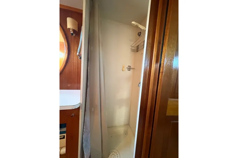 Slide: The Image of 1975 Gulfstar 43 Trawler bathroom with shower, wooden accents, and round mirror. - 57