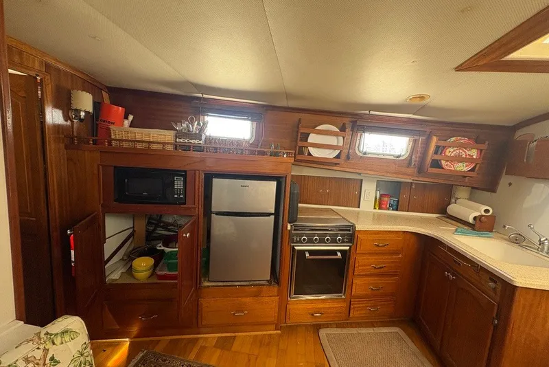 Slide: The Image of 1975 Gulfstar 43 Trawler kitchen with wooden cabinetry, microwave, fridge, and stove. - 38