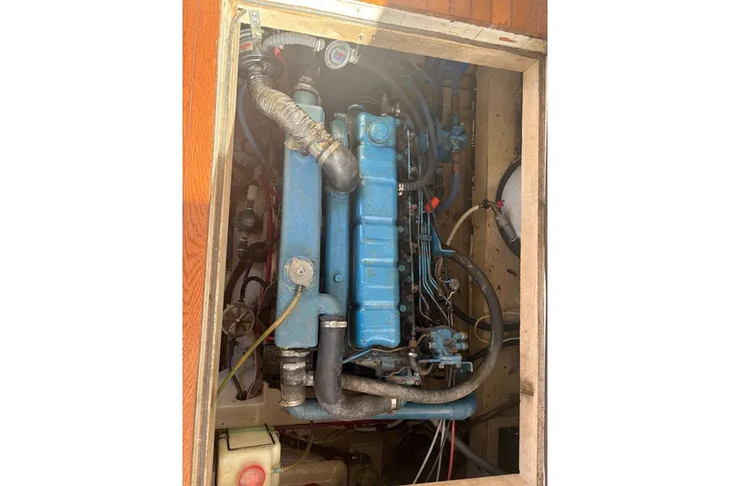 Slide: The Image of Engine compartment of a 1975 Gulfstar 43 Trawler, showcasing blue machinery and hoses. - 104