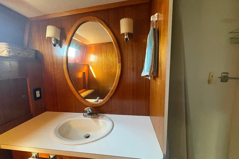 Slide: The Image of 1975 Gulfstar 43 Trawler bathroom with oval mirror, wooden paneling, and sink. - 58