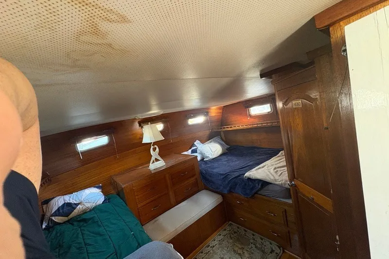 Slide: The Image of Cozy cabin interior of a 1975 Gulfstar 43 Trawler with wooden furnishings and bedding. - 52