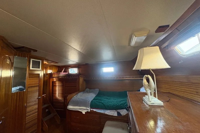 Slide: The Image of Cozy cabin interior of a 1975 Gulfstar 43 Trawler with wooden furnishings and a decorative lamp. - 61