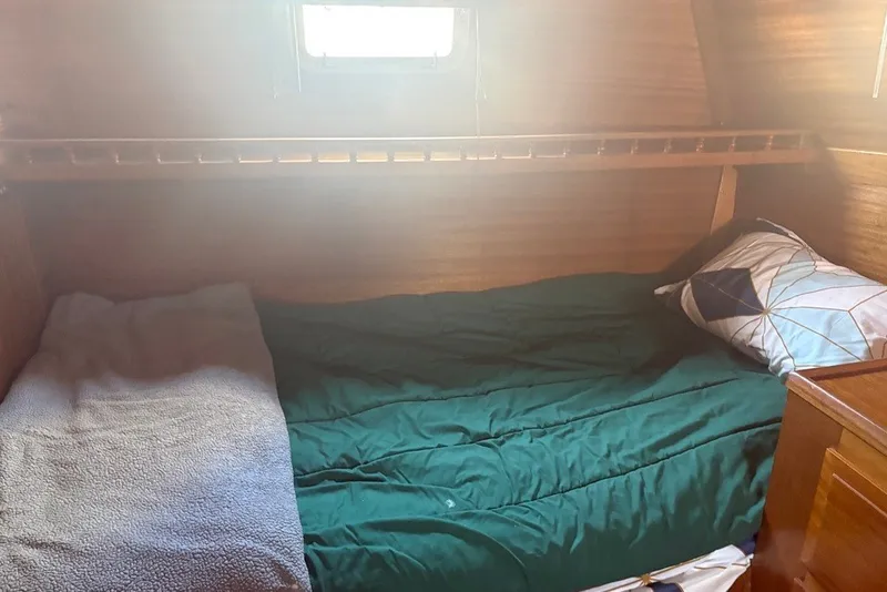 Slide: The Image of Cozy cabin bed inside a 1975 Gulfstar 43 Trawler, featuring wooden walls and a small window. - 65