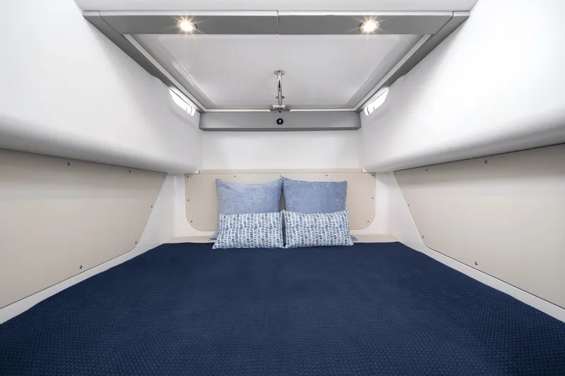 Slide: The Image of The cabin of the 2027 Cruisers Yachts 38 VTR features a cozy bed with blue pillows. - 33