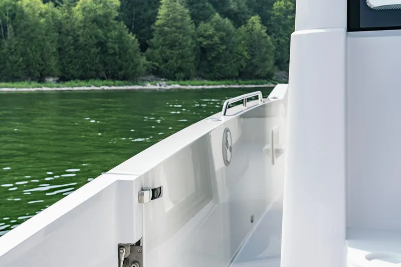 Slide: The Image of A modern boat with a sleek white railing, cruising on a calm lake with green trees. - 18