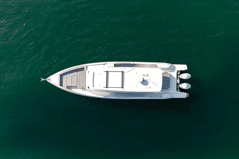 Slide: The Image of Aerial view of a sleek white yacht on calm water, featuring two outboard engines and a spacious deck. - 38