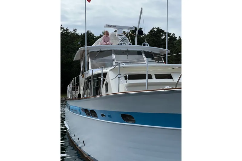 Slide: The Image of 1962 Chris-Craft 55 Commander yacht with blue accents, docked near lush greenery. - 14