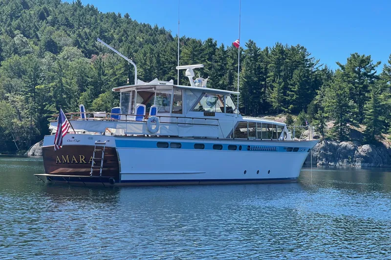 Slide: The Image of 1962 Chris-Craft 55 Commander yacht on serene lake with forested backdrop. - 16