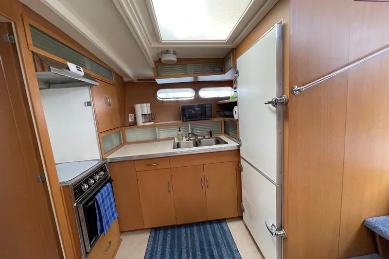 Slide: The Image of 1962 Chris-Craft 55 Commander kitchen with wooden cabinetry, stove, sink, and refrigerator. - 32