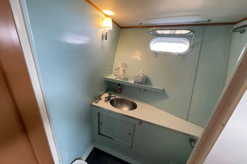 Slide: The Image of 1962 Chris-Craft 55 Commander bathroom with light blue walls, porthole, and stainless steel sink. - 37