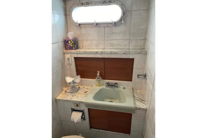 Slide: The Image of 1962 Chris-Craft 55 Commander bathroom with sink, porthole, and marble accents. - 40