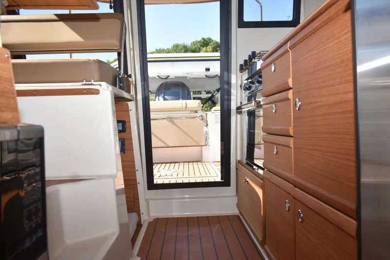 Slide: The Image of 2024 Ranger Tugs R-27 interior with wood cabinetry and modern appliances. - 41