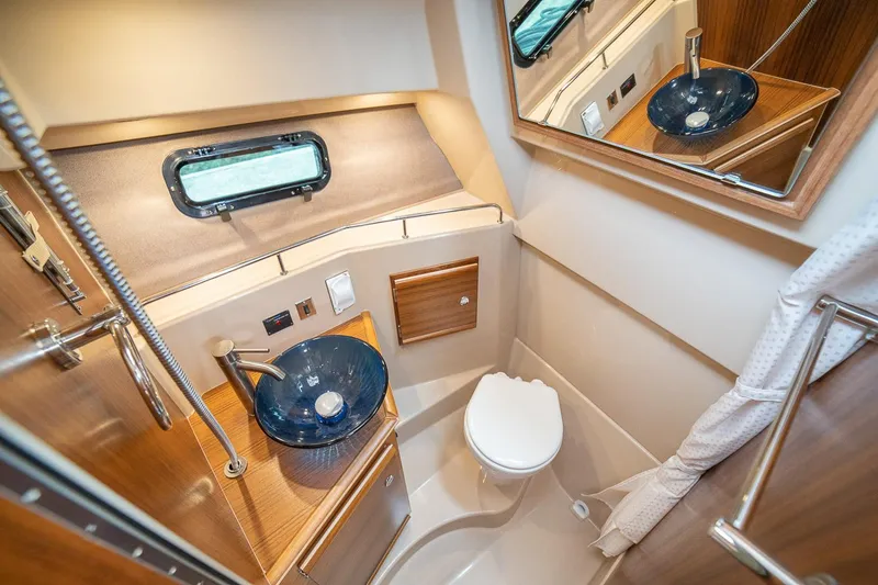 Slide: The Image of Manufacturer Provided Image: 2024 Ranger Tugs R-27 bathroom with modern sink, toilet, and wood accents. - 55