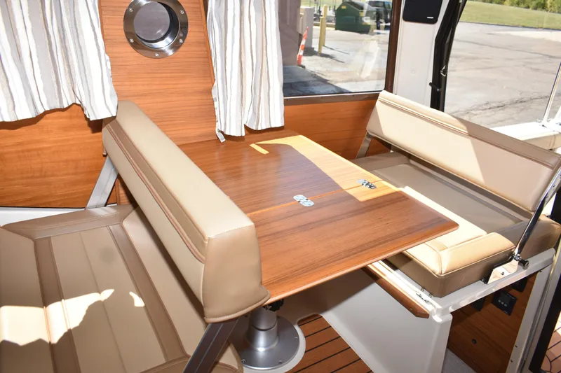 Slide: The Image of 2024 Ranger Tugs R-27 interior with wood table and beige seating. - 52