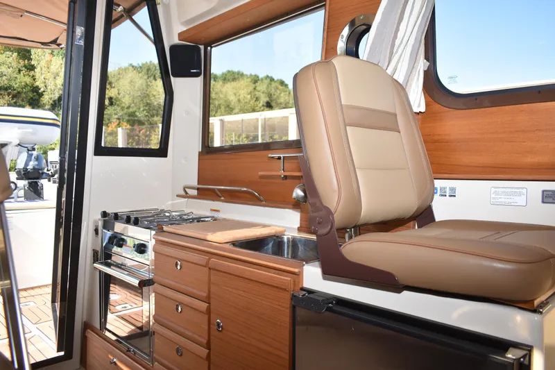 Slide: The Image of 2024 Ranger Tugs R-27 interior with kitchen, seating, and window view. - 36