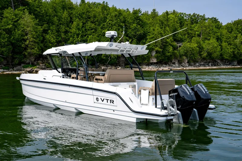 Slide: The Image of A modern motorboat with twin outboard engines, floating on calm water near a wooded shoreline. - 4