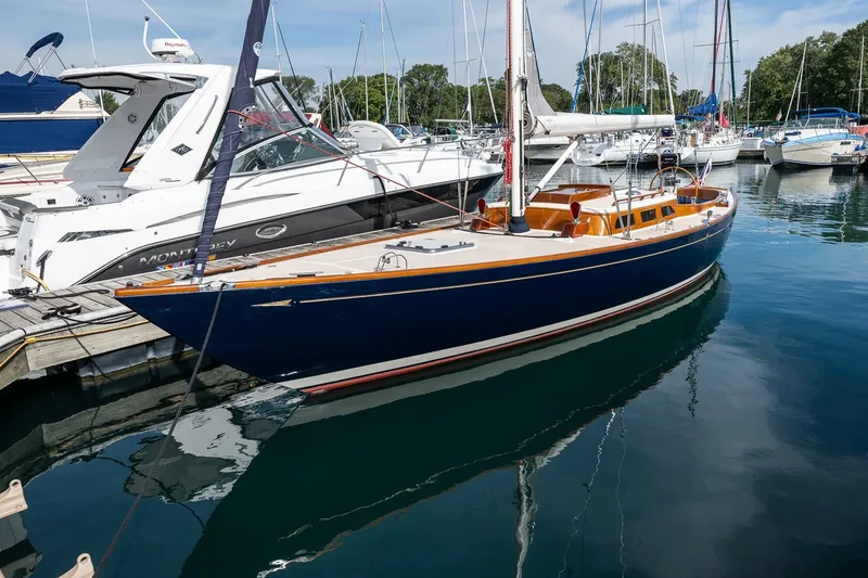 Slide: The Image of Sleek 2009 Morris M36 sailboat docked in a marina, surrounded by other boats. - 1