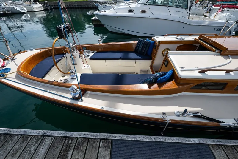 Slide: The Image of 2009 Morris M36 sailboat docked, featuring elegant wooden trim and blue cushioned seating. - 8