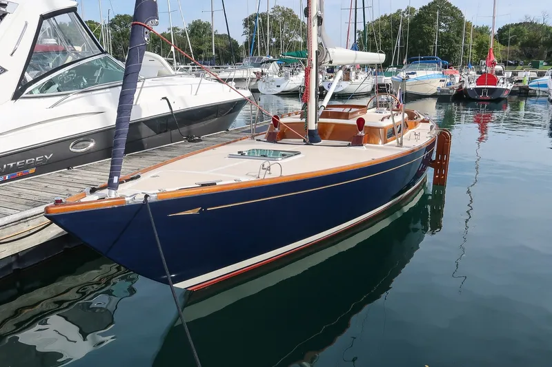 Slide: The Image of Sleek 2009 Morris M36 sailboat docked in a marina, surrounded by other boats. - 2