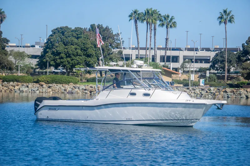 Slide: The Image of 2005 Boston Whaler 305 Conquest boat cruising near a scenic shoreline. - 2